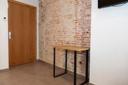 a room with a wooden table next to a brick wall at Hostal Paris in Barcelona