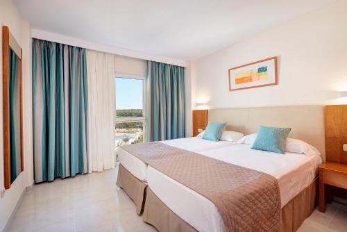 een hotelkamer met een groot bed en een raam bij Hipotels Coma Gran in Sa Coma