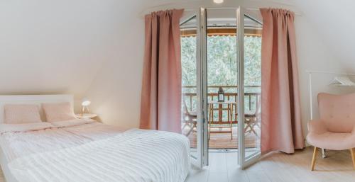 a bedroom with a bed and a balcony with a chair at Hej na Mazury Apartamenty in Ruciane-Nida