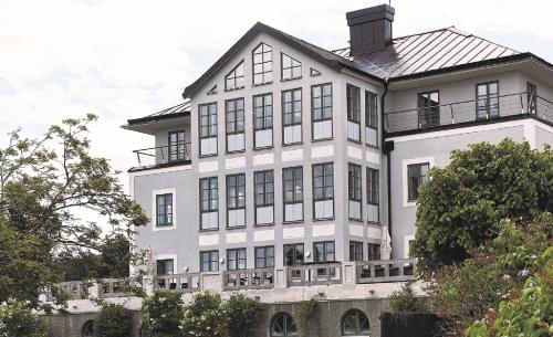 a large white building with a black roof at Sands Hotell in Sandhamn