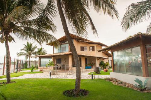 a house with palm trees in front of it at Pousada Cores dos Corais in Maracajaú