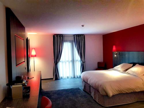 a bedroom with a large bed and a red wall at Les Maritonnes Parc & Vignoble in Romanèche-Thorins