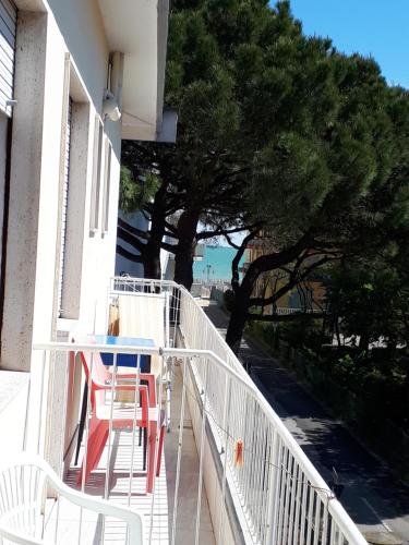 a balcony with two chairs and a table and a tree at Hotel Villa Dina in Lido di Jesolo
