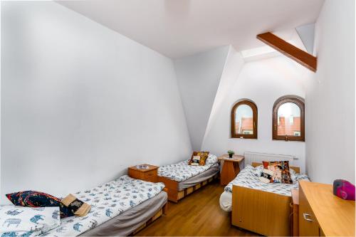 斯塞新的住宿－Strych Kościuszki - duży，配有白色墙壁和木地板的客房内的三张床