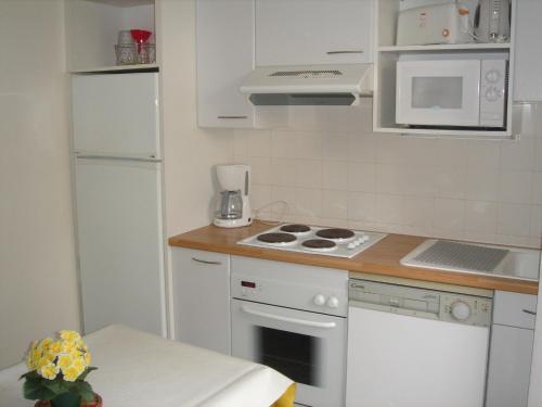 une petite cuisine avec des appareils électroménagers blancs et une table dans l'établissement Villa Etche Xuria, à Biscarrosse-Plage