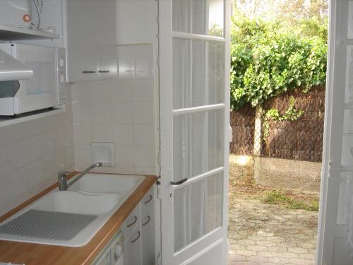 une cuisine avec un évier et une porte ouverte dans l'établissement Villa Etche Xuria, à Biscarrosse-Plage