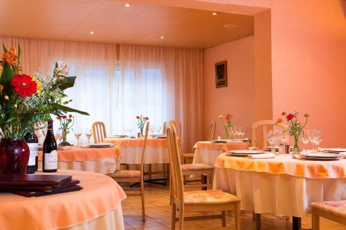 un comedor con mesas y sillas con flores. en Hôtel Le Montaigu, en Luz-Saint-Sauveur