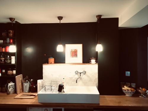 une cuisine avec un évier blanc et un mur noir dans l'établissement Elegant and cosy flat near Montmartre, à Paris