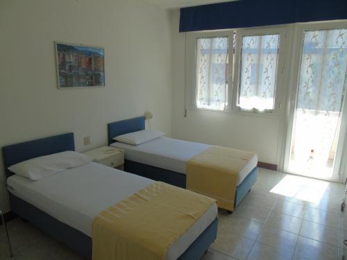 a bedroom with two beds and two windows at Villa Valeria in Lignano Sabbiadoro