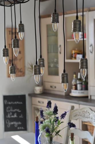 une cuisine avec plusieurs lumières suspendues au-dessus d'une table dans l'établissement La Bastide Du Bonheur Chambres et Tables D'Hôtes, à Ger