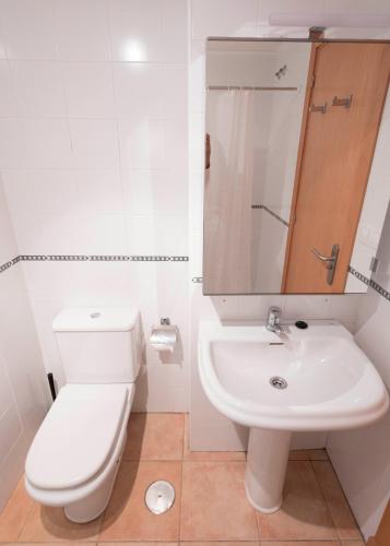 a white bathroom with a toilet and a sink at Mar y tierra in Conil de la Frontera