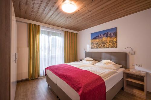 una camera da letto con un grande letto con una coperta rossa di Appartementhaus Mühlberger a Ellmau