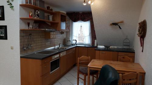 eine Küche mit Holzschränken, einem Tisch und einem Fenster in der Unterkunft Ferienwohnungen Mentges in Mesenich