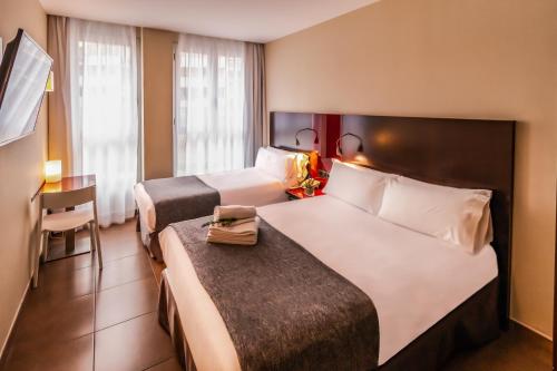 a hotel room with two beds and a table at SM Hotel Teatre Auditori in Barcelona