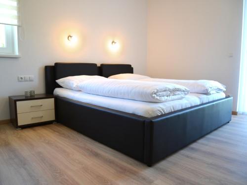 Bett mit schwarzem Rahmen und weißer Bettwäsche in der Unterkunft Haus Senel in Eben im Pongau