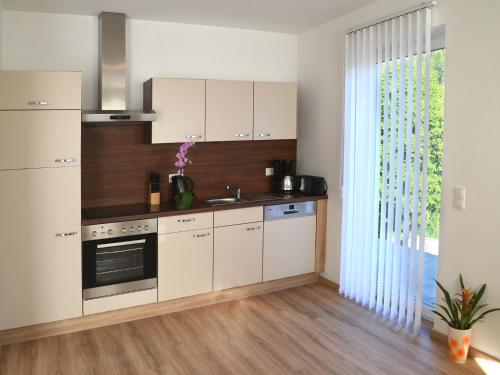 a kitchen with white cabinets and a large window at Haus Senel in Eben im Pongau