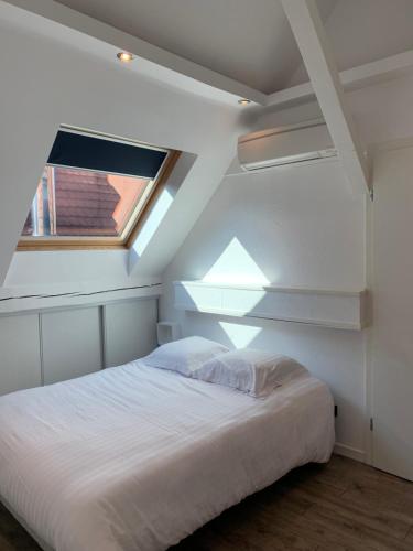 1 dormitorio con cama blanca y ventana en Appart LE COUCOU, en Saint-Hippolyte