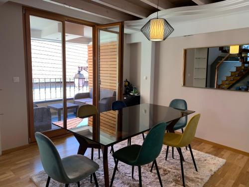 une salle à manger avec une table noire et des chaises vertes dans l'établissement Appart LE COUCOU, à Saint-Hippolyte