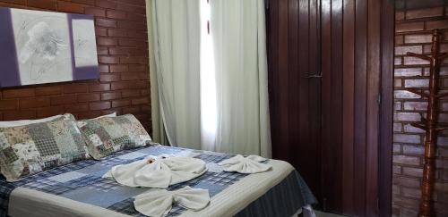 a bedroom with a bed with towels on it at Pousada Portal da Barra in Marataizes