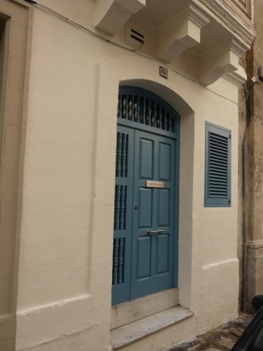 a blue door on a building with wine bottles at Zekka Studio in Valletta