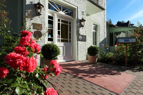 a front door of a house with red flowers at Seehotel Ecktannen in Waren