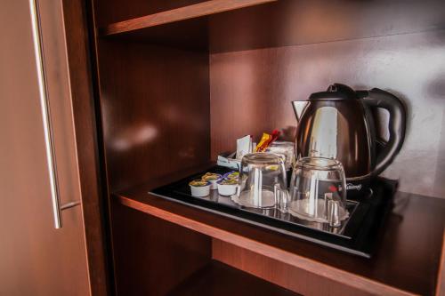 a tea kettle and cups on a shelf in a microwave at SM Hotel Teatre Auditori in Barcelona
