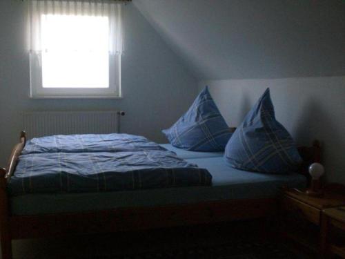 Un dormitorio con una cama con almohadas azules y una ventana en Letztes-Haus-vorm-Wasser-1, en Strukkamp auf Fehmarn