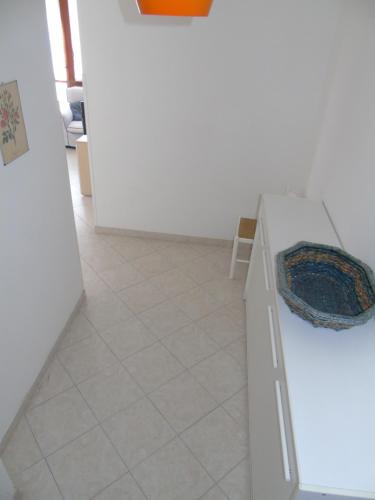 a kitchen with a white counter and a tile floor at Condominio Imperiale in Lignano Sabbiadoro