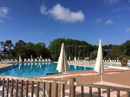 - une piscine avec des chaises et des parasols blancs dans l'établissement Appartement 2 Pièces Port-Bourgenay 31m2 - Accès piscine inclus, à Talmont-Saint-Hilaire