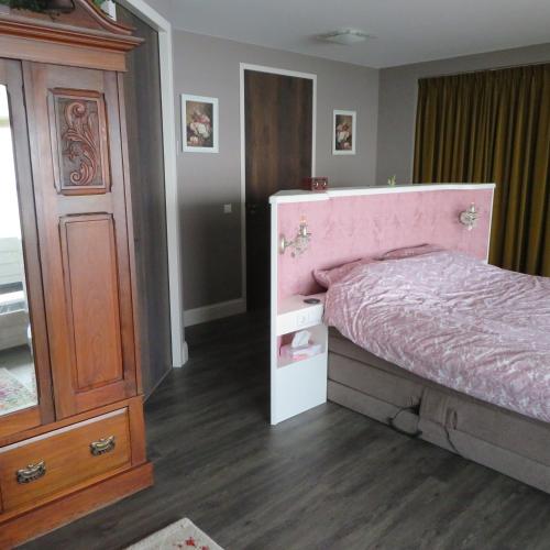 a bedroom with a pink bed and a wooden cabinet at Villa Braas in Breukeleveen