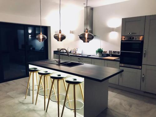 a kitchen with a island with bar stools at Eden Cottage in Frodsham