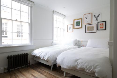 2 camas en un dormitorio con paredes y ventanas blancas en Grade II Listed Townhouse in heart of the City - FREE DESIGNATED PARKING, en Bath