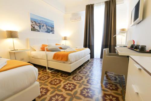 a hotel room with two beds and a desk at Le Stanze di Piazza Cairoli in Messina
