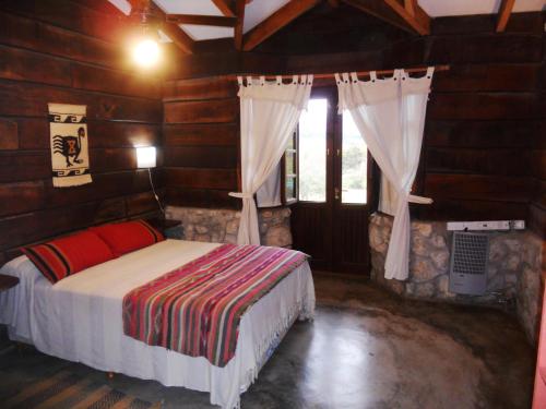1 dormitorio con 1 cama en una cabaña de madera en Posada La Ensenada en Villa Yacanto