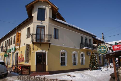 a yellow building with a christmas tree in front of it at Hotel Zorepad in Zabolotiv