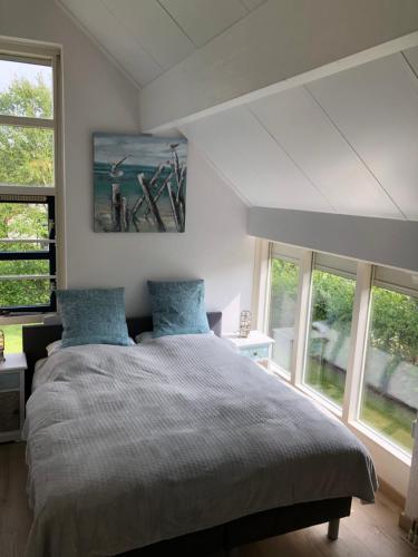 a bedroom with a large bed with blue pillows at Villa Ooghduyne 82 in Julianadorp