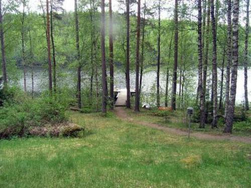 a path through a forest next to a body of water at Holiday Home Sokeelampi by Interhome in Matku