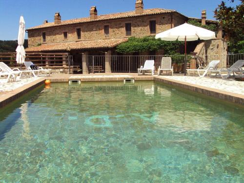 a large swimming pool with chairs and an umbrella at Agriturismo Selvella in Allerona