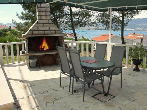 eine Terrasse mit einem Tisch, Stühlen und einem Kamin in der Unterkunft Apartment Anđa-4 by Interhome in Trogir