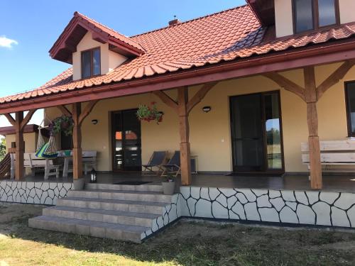 a house with a porch with a roof at Przytulisko na Mazurach in Ruciane-Nida