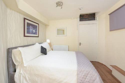 a bedroom with a white bed and white walls at Central London Rooms in London
