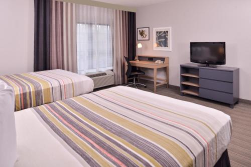 a hotel room with two beds and a desk and a television at Country Inn & Suites by Radisson, Raleigh-Durham Airport, NC in Morrisville