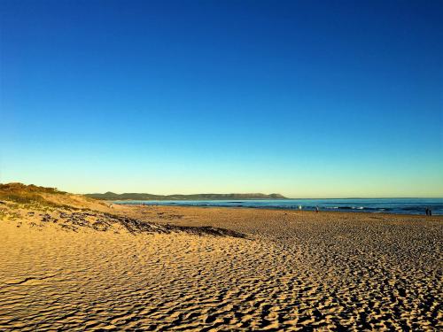a sandy beach with the ocean in the background at The Gables Hermanus in Hermanus