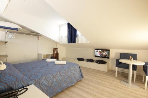 - une chambre avec un lit, une table et une télévision dans l'établissement Hotel Serenella, à Lido di Jesolo