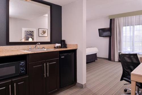 Habitación de hotel con lavabo y dormitorio en Country Inn & Suites by Radisson, Raleigh-Durham Airport, NC en Morrisville