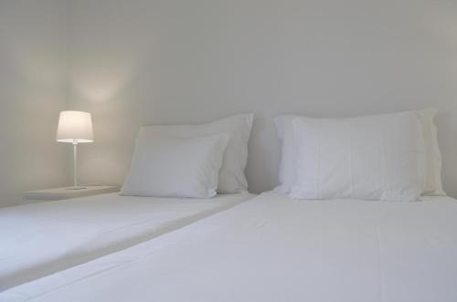 a white bed with white pillows and a lamp at Apartamentos Turísticos Vitoria by Petit Hotels in Funchal