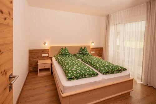 una camera da letto con un letto con piumone e cuscini verdi di Apartments Sankt Walburg a Anterselva di Mezzo
