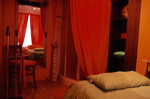 クヴェードリンブルクにあるReikistudio "Auszeit"の赤いカーテン、ベッド、鏡が備わるベッドルーム1室が備わります。