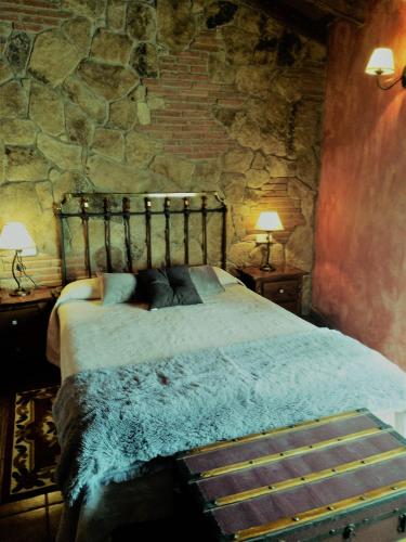 a bedroom with a bed in a stone wall at El Cerrillo 1 in San Martín del Pimpollar