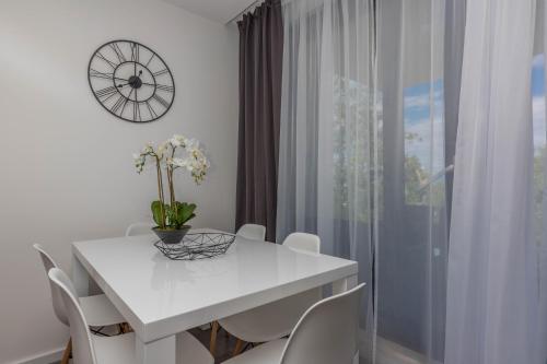 a white dining room table with white chairs and a clock at Apartments Ines in Selce